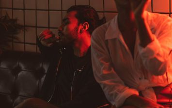 A relaxed and intimate setting with two adults in a dimly lit lounge under red light.